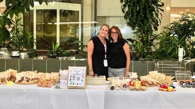 Two Marcus Ave. teachers behind a table of snacks at Back-to-School Night