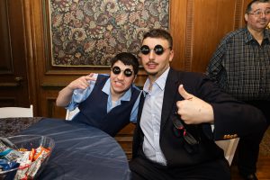 Two BCCS students wear sunglasses that read "Prom 2026" and give thumbs up at prom
