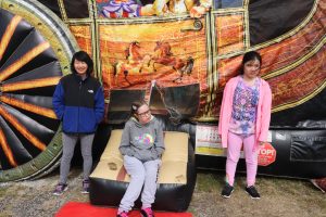Three residents of the Children's Residential Program in front of a bouncy house at the Fall Festival