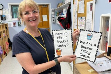 A BCCS teacher poses with the Bucket Filler artwork