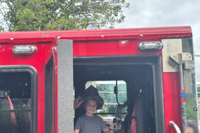 A BCCS student wears a firefighter's helmet inside a firetruck at the touch-a-truck event